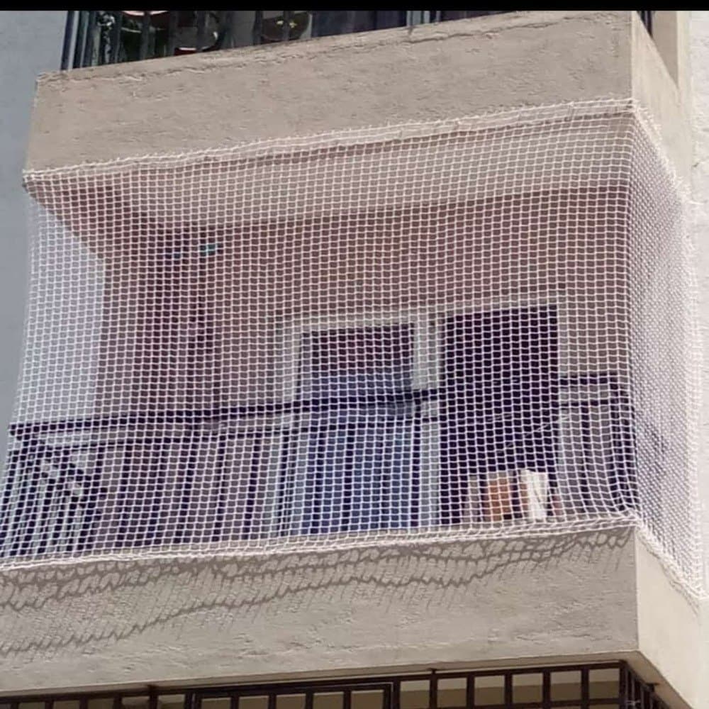 UV-stabilized HDPE balcony safety net mounted securely with SS 304 anchor hooks on high-rise flat balcony - AJ Safe Net Solutions